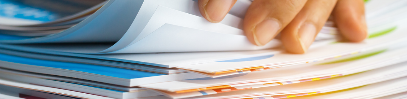 A hand of someone sorting through a stack of papers