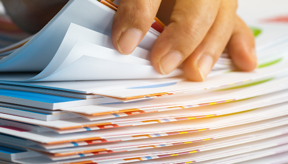 A hand of someone sorting through a stack of papers