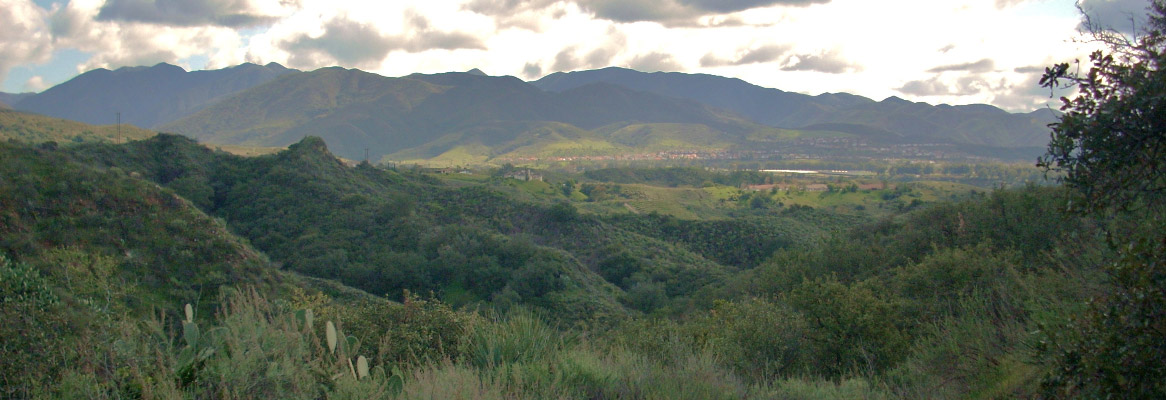 A panorama of clouds over a mountain range and green field